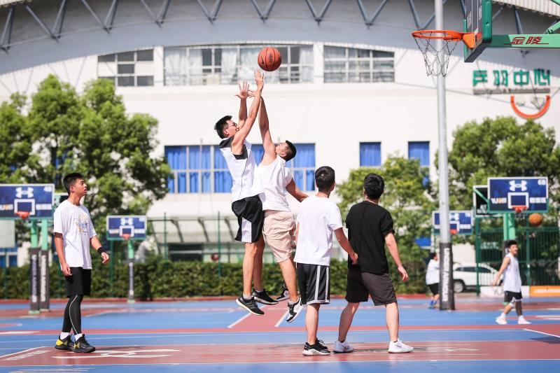 篮球爱好者来到源深体育中心室外篮球场打球.