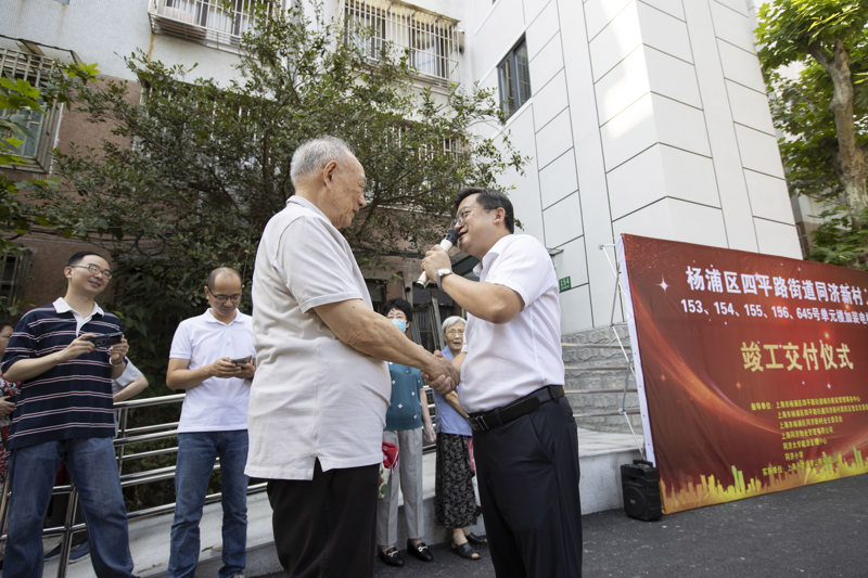 宣国荣老人握住居委书记的张立民的手，连声道谢。