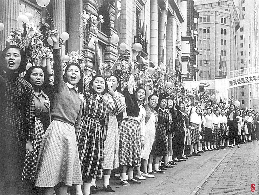 1952年10月1日，上海女性手持鲜花，向参加国庆游行的部队同志欢呼致敬。