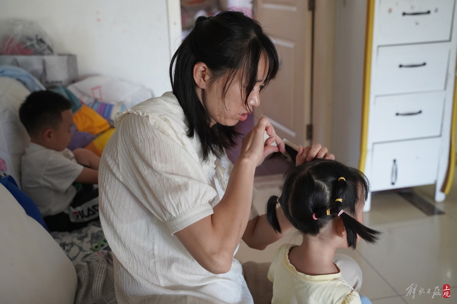 “左邻右舍”的保育员老师正在帮刚睡醒的小女孩扎头发。