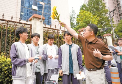 6月7日上午，2026年高考拉开帷幕。在上海外国语大学附属大境中学考点外，来送考的上海市第八中学老师准备了向日葵贴纸，并举起向日葵，祝福考生们“一举夺魁”。  本报记者  孟雨涵  摄