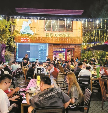 老外街的德国乡村餐厅门口摆好了巨幅电视。  资料图片