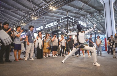 机器人展示灵活舞步，引来观众围观。  本报记者  孟雨涵  摄