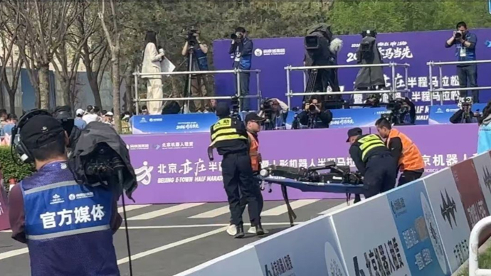 宇树H1机器人半马赛场终点“累倒”，现场视频：工作人员紧急用担架将其抬离