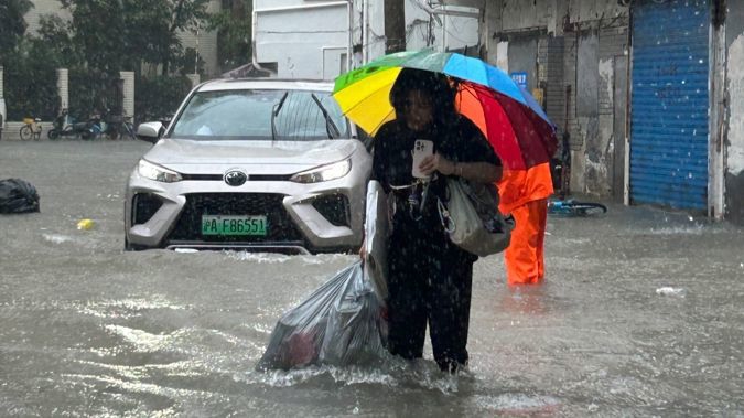 大风大雨中，社区干部拖着装满垃圾的塑料袋趟水前行，上海多方联动守护平安