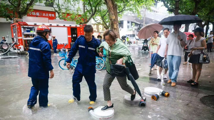 排涝现场，消防员巧设“水带桥”，暖到市民心坎里 | 新民特写