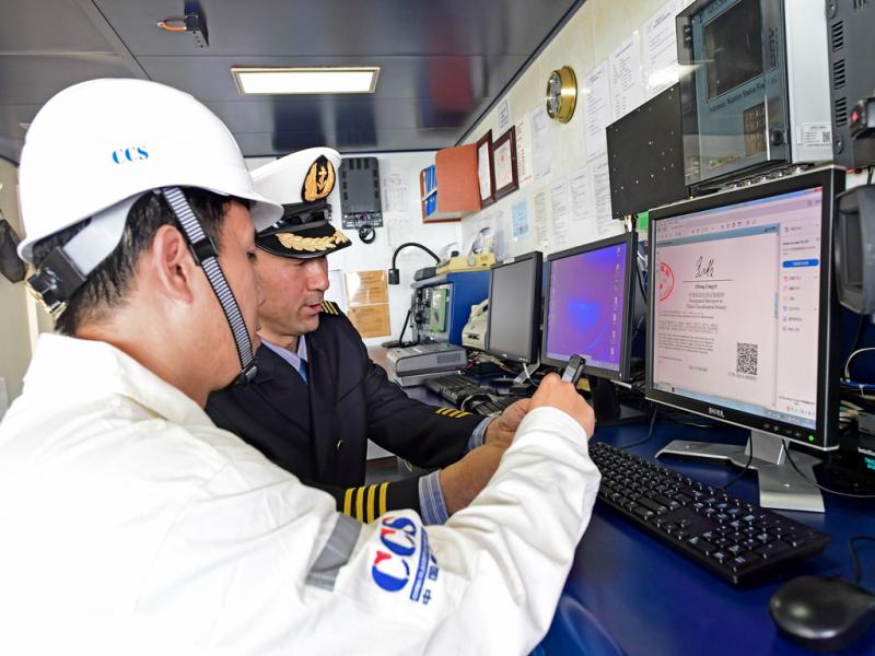 中国籍国际航行船舶“新美洲”轮船长（右）通过电邮软件，即刻收到了中国船级社签发的首份电子证书。（上海海事局 陈方摄）