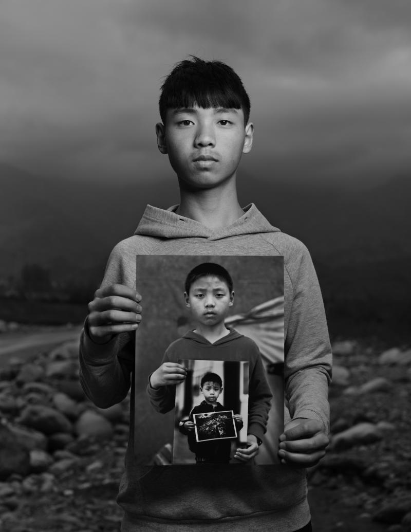 地震幸存者6岁的小男孩刘世杰坐在救灾篷里往外看.